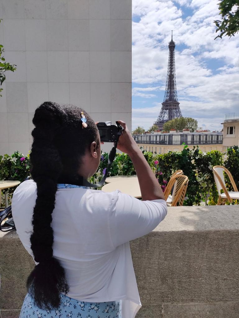 Martha taking a picture of the Eiffel Tower and enjoying the scenery and benefits of moving abroad