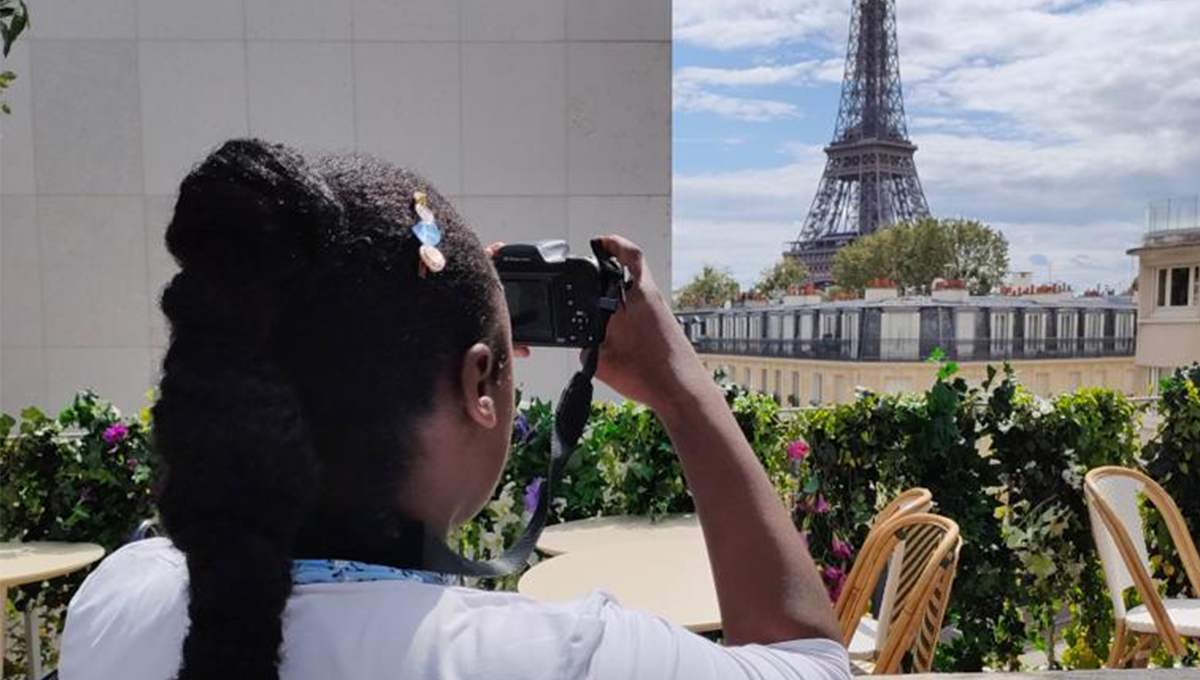 Martha taking a picture of the Eiffel Tower and enjoying the scenery and benefits of moving abroad